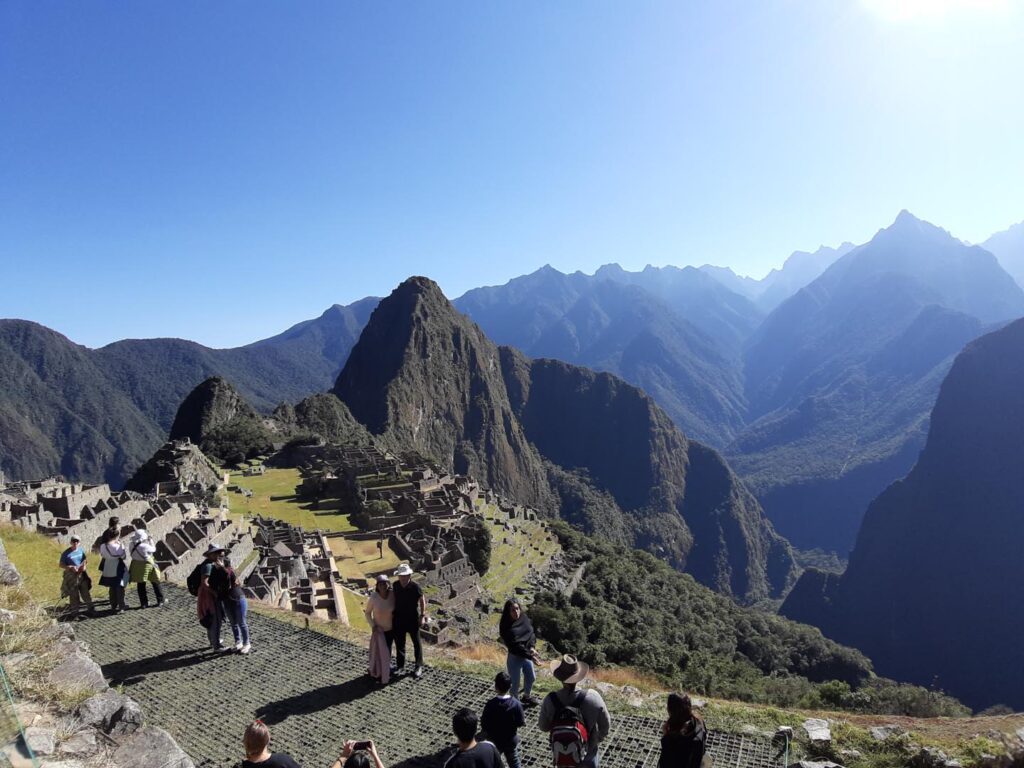 Machu Picchu, un dia cuando hace sol, con gente disfrutando, tomando fotos